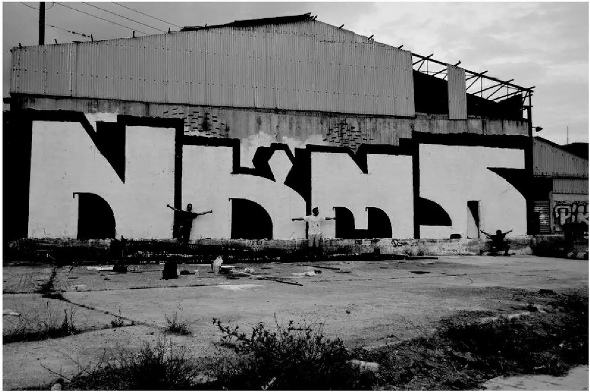 The NKMS crew in front of a large black and white NKMS graffiti on a warehouse wall in Loutraki, 2013